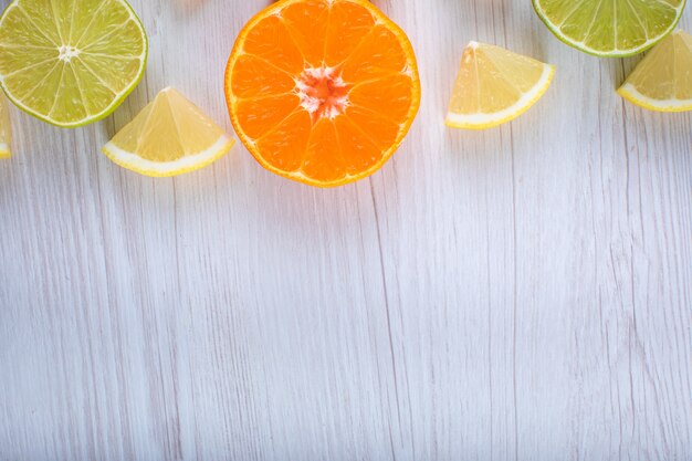柑橘系の果物は木製の表面にレモンオレンジライムトップビューをスライス