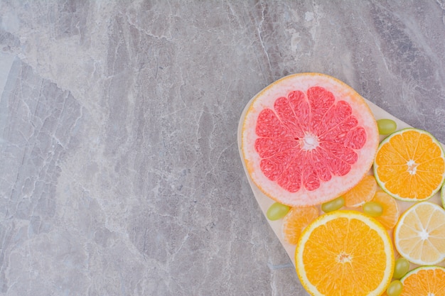 Free photo citrus fruits slices and grapes on wooden board.