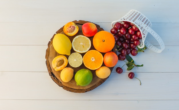 さくらんぼ、アプリコット、ネクタリンと柑橘系の果物はまな板と木製の背景にフラットレイアウト