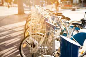 Free photo city bicycles with metal basket for rent stand in a row on a cobbled street