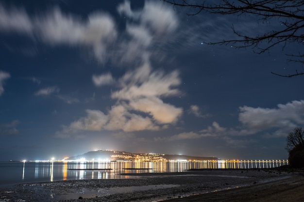 City lights and night sky from the Sandsfoot beach in Dorset, UK