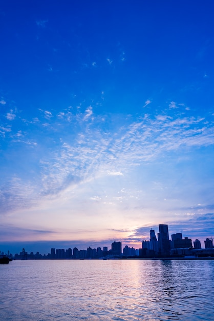 Free Photo city skyline by river against cloudy sky