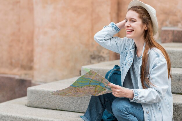 City traveller holding a map and sitting on stairs