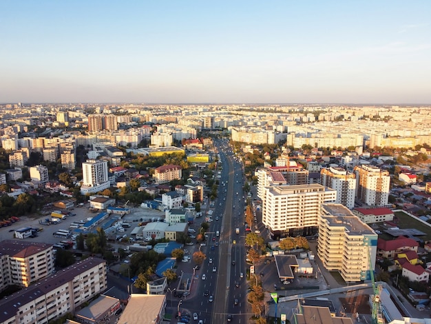 Городской пейзаж Бухареста, дорога с движущимися автомобилями, несколько жилых домов, чистое небо, вид с дрона, Румыния