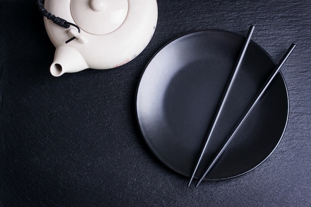 Clack plate with chopsticks and a teapot