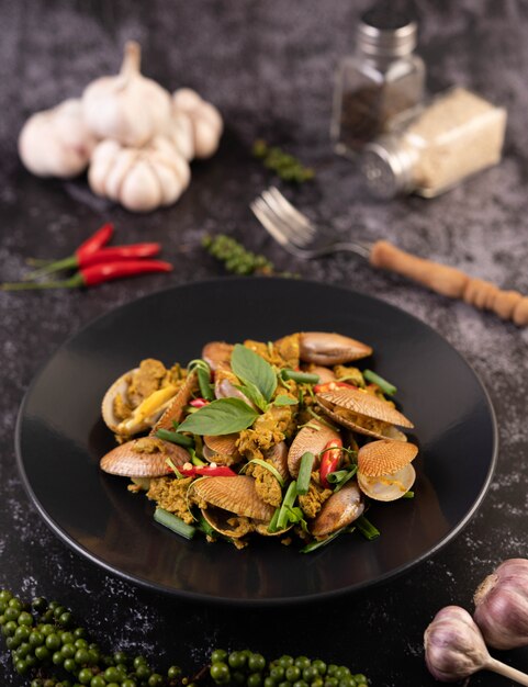 Clams fried curry powder on a black plate.