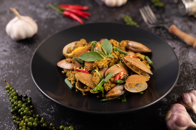 Free photo clams fried curry powder on a black plate.