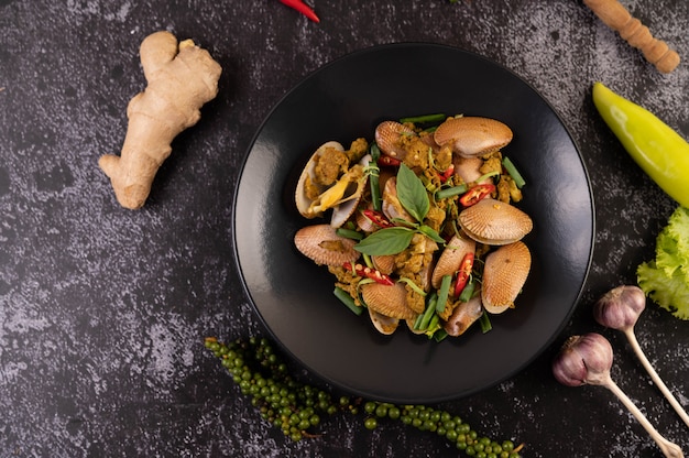 Clams fried curry powder on a black plate.