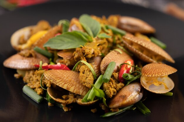 Clams fried curry powder on a black plate.