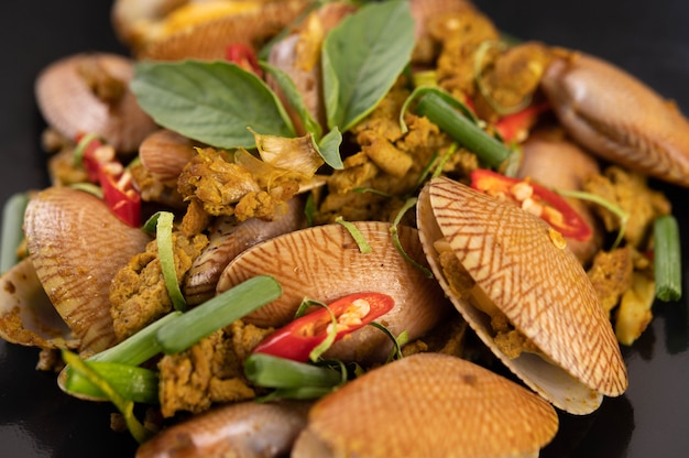 Clams fried curry powder on a black plate.