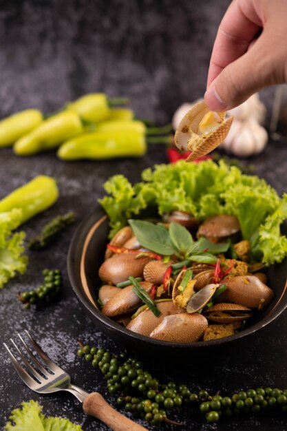 Clams fried curry powder on a black plate.