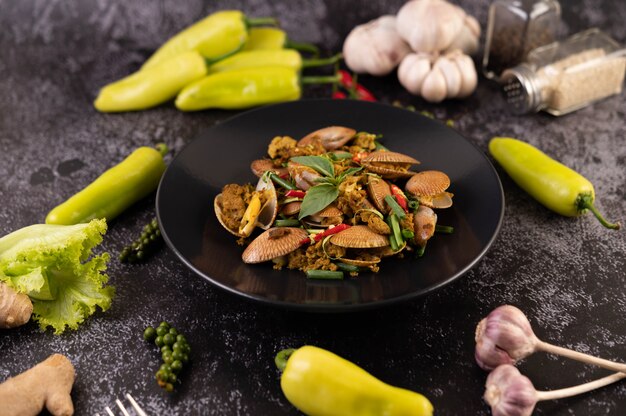 Clams fried curry powder on a black plate.