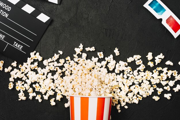 Clapperboard and 3D glasses near popcorn