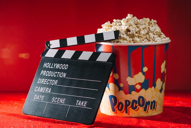 Free photo clapperboard leaning against big popcorn bucket