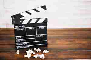 Free photo clapperboard and popcorn on lumber tabletop