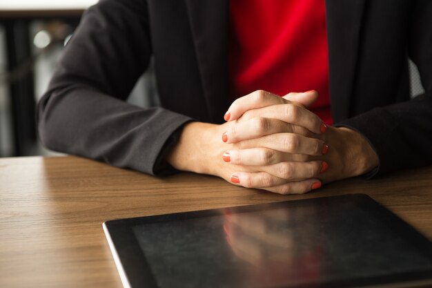 Clasped hands of businesswoman and digital tablet