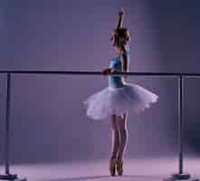Бесплатное фото Классическая балерина позирует в балетном баре