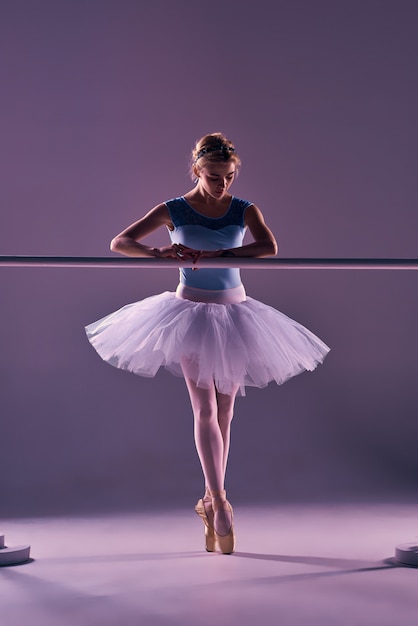 Ballerina classica che propone alla sbarra di balletto