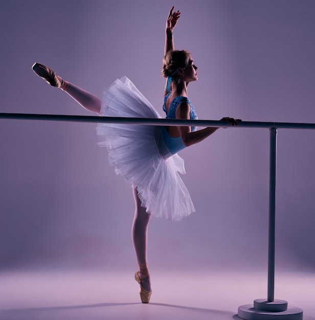 Foto gratuita ballerina classica che propone alla sbarra di balletto