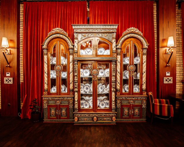 Classic china cabinet in front of the red long curtains at restaurant hall