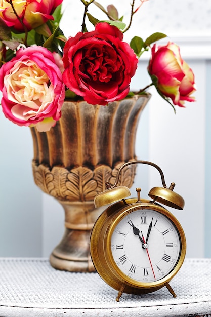 классические часы-часы в ярком красочном ретро интерьере за красными цветами
