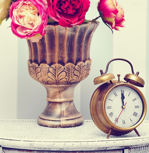 classic clock  watch in bright colorful retro interior behind red flowers