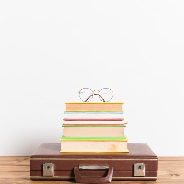 Классические очки на стопку книг на винтажном чемодане