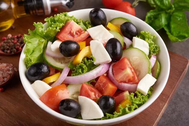 新鮮な野菜、きゅうり、トマト、ピーマン、レタス、赤玉ねぎ、フェタチーズ、オリーブとオリーブオイルのクラシックなギリシャ風サラダ。健康食品、上面図
