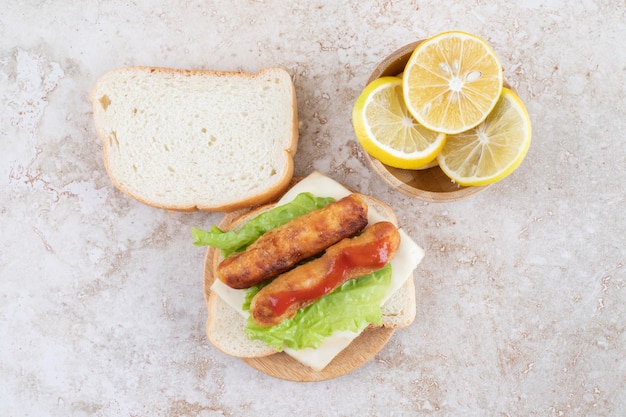 Free photo classic grilled sausage sandwich with lettuce and lemons.