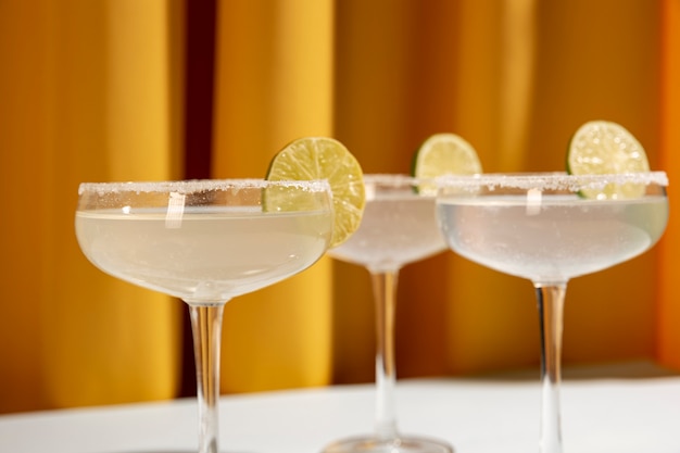 Classic lime margarita cocktail with sliced limes against yellow curtain