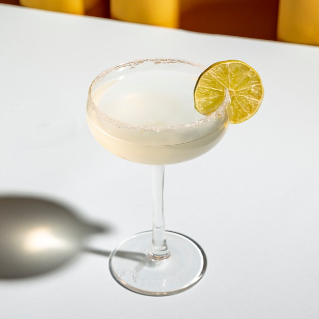 Classic margarita cocktail with salt on the edge of saucer glass on white table