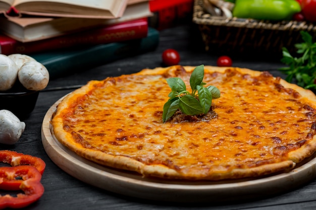完全に溶けたチェダーチーズと新鮮なバシリカの葉が付いたクラシックなマルガリータピザ