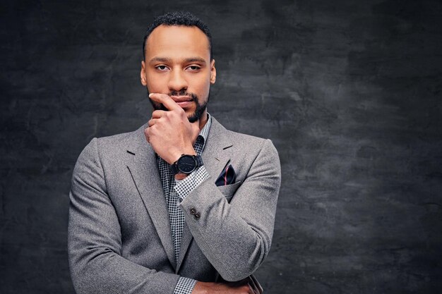 Classic studio portrait of black American male dressed in a suit over grey vignette background.