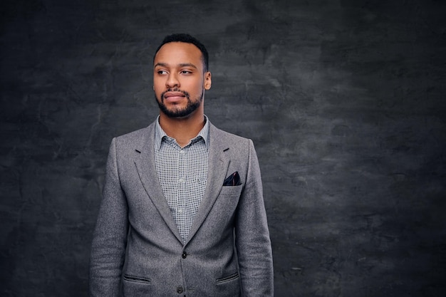 Classic studio portrait of black American male dressed in a suit over grey vignette background.