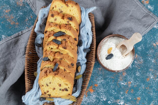 Classic sultana pie slices on wooden basket on blue towel.