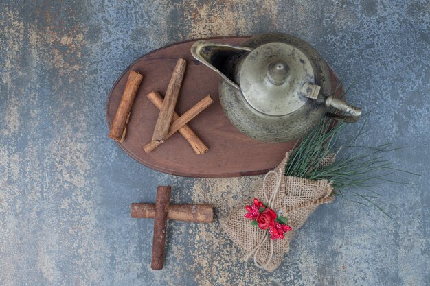 Classic teapot and cinnamon sticks on wooden plate. High quality photo