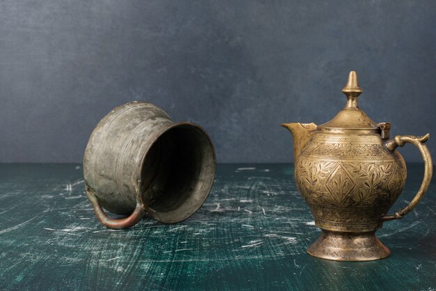 Classic teapot and vase on marble table.