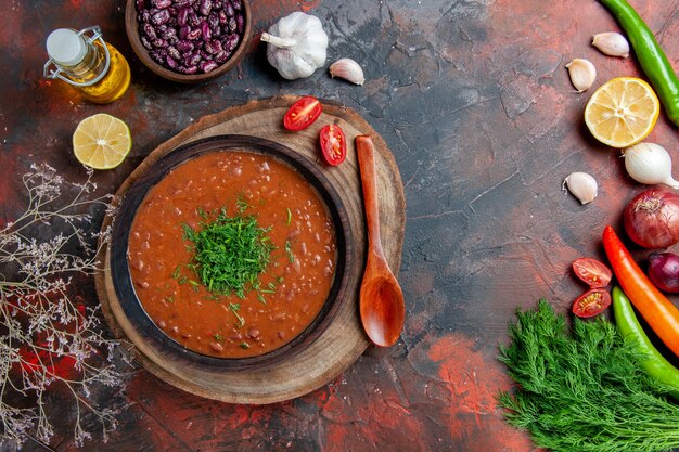 茶色のボウルオイルボトル豆と混合色のテーブルのスプーンで古典的なトマトスープ