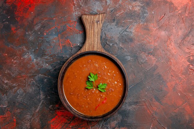 Classic tomato soup on a brown cutting board on mixed color table