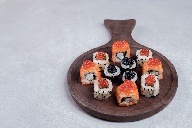 Классический выбор суши-роллов на деревянной доске с палочками для еды.