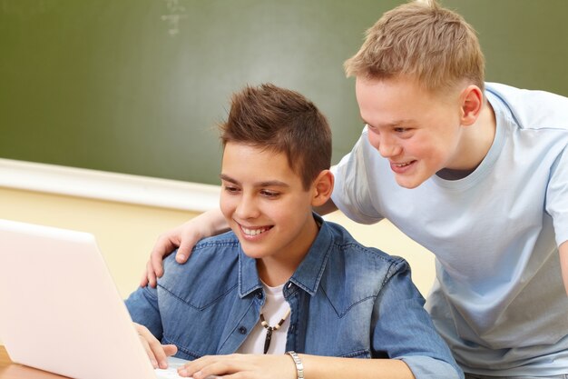 Classmates laughing with laptop