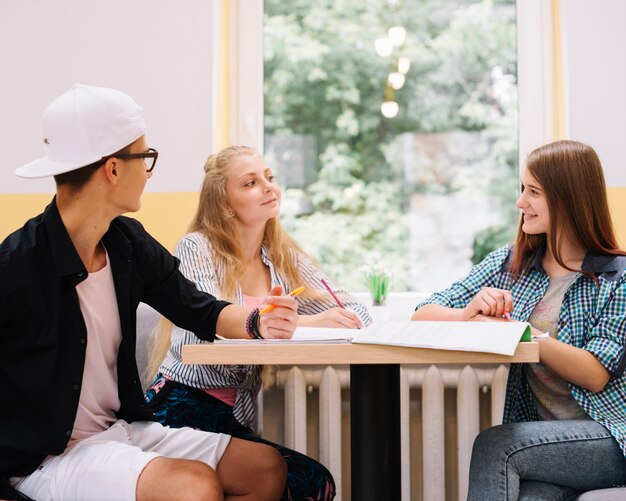 Classmates with books at desk