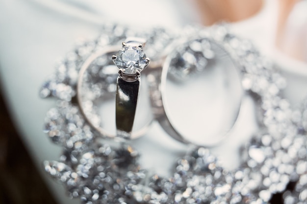 화이트 골드 소재의 고급 실버 결혼 반지가 크리스탈 브레이슬릿에 놓여 있습니다.
