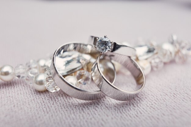 Стильные серебряные обручальные кольца из белого золота лежат на хрустальном браслете