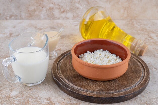 A clay bowl of cottage cheese with milk and a glass bottle of oil 