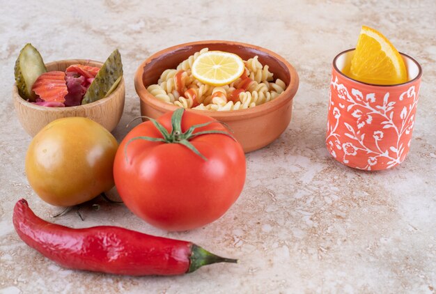 A clay bowl of delicious pasta with various vegetables 