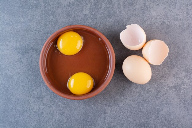 Clay bowl of egg yolk placed on stone table.