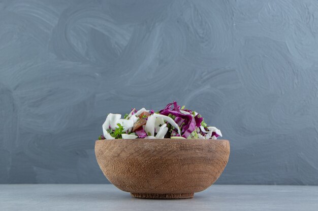 A clay bowl of mixed vegetables , on the marble.