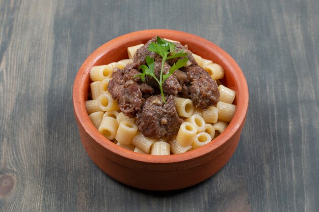 A clay bowl with delicious macaroni and meat