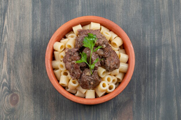 A clay bowl with delicious macaroni and meat